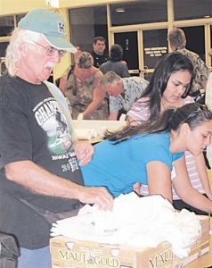 Kihei Community Association Vice President and Services Committee Member Mike Moran distributes cloth grocery bags to be used as alternatives to plastic bags.